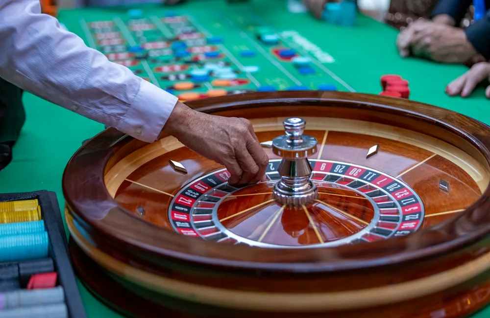 Roulette wheel and ball at rest on a dark casino table under studio lighting