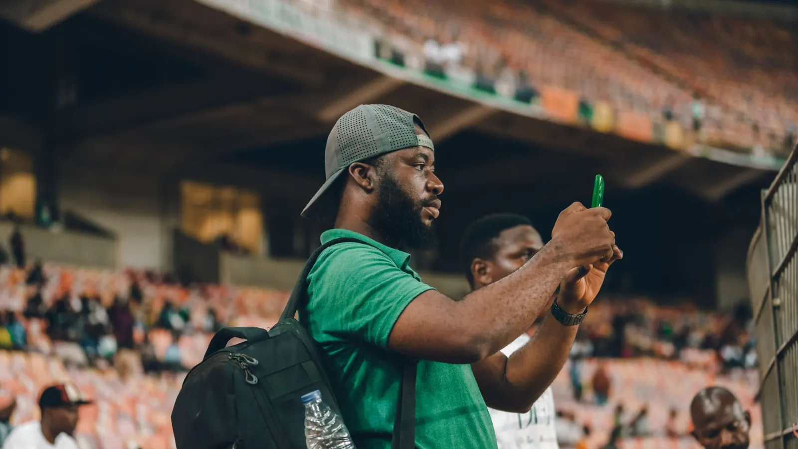 Person holding a smartphone at the track rail placing real money sports gambling bets